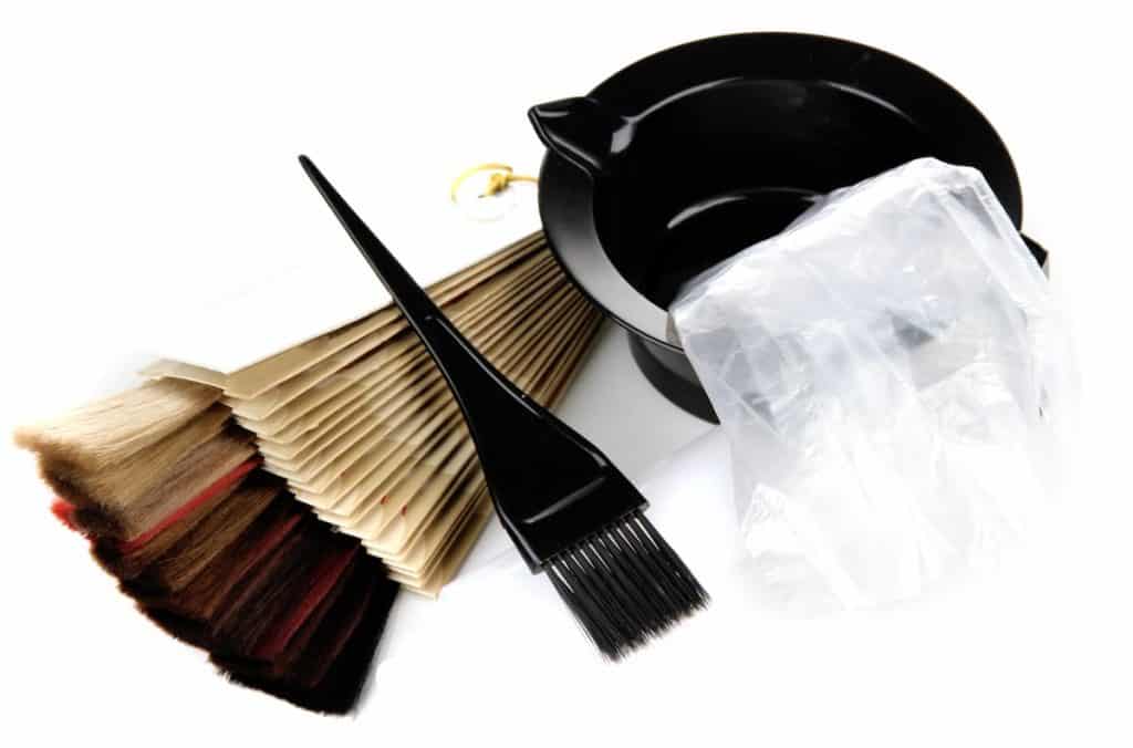 A black comb, brush and hair color on a white background.