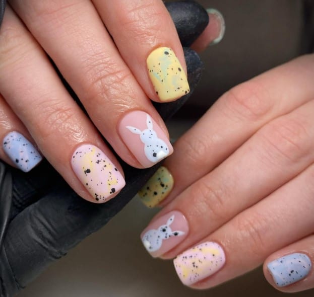 A woman's hands with marble designs and a matte finish with a bunny on the accent nail