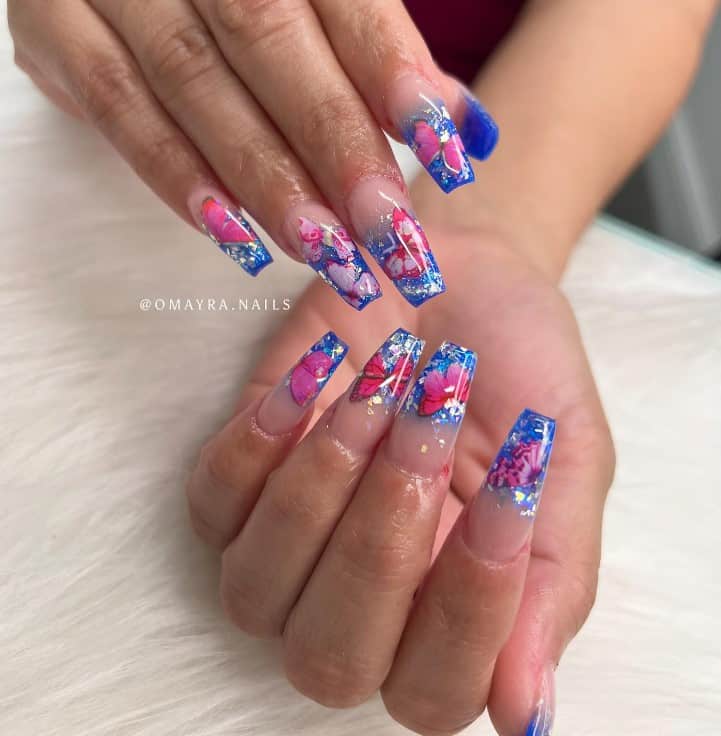 A woman's nails with royal blue nails than with butterflies and ombré tips