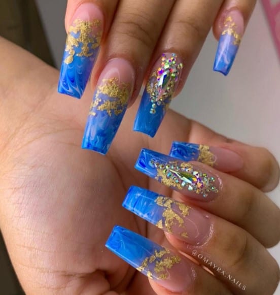 A woman with watercolor effect in negative space and blue marble ombré tips flecked with gold foil