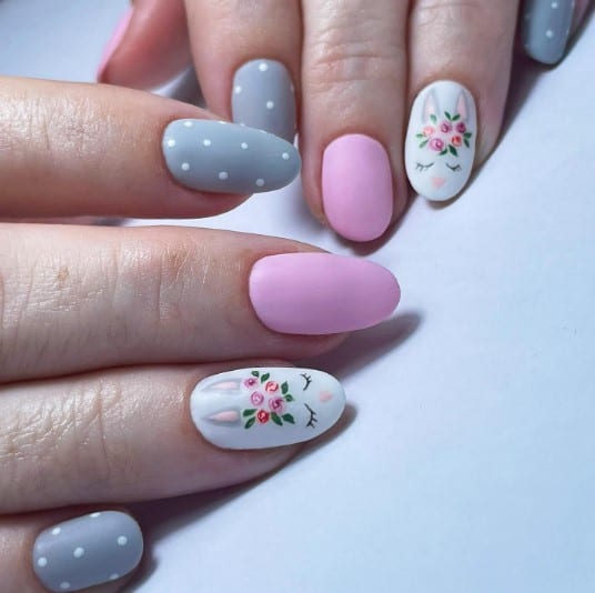 A woman's matte blue nails with polka dots and plain pink nails