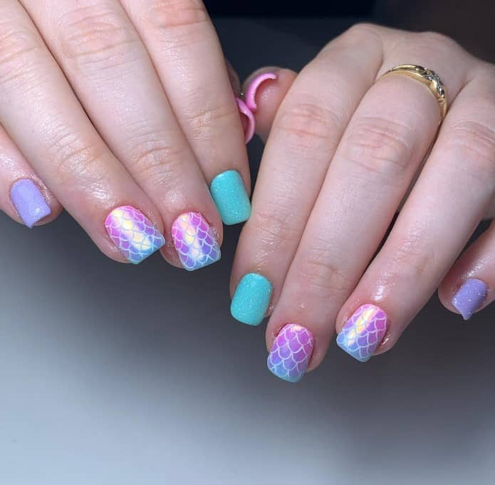 pastel-colored mani that features shimmery pink, blue, and purple nails, along with mermaid scales on ombre pink-and-blue accent nails