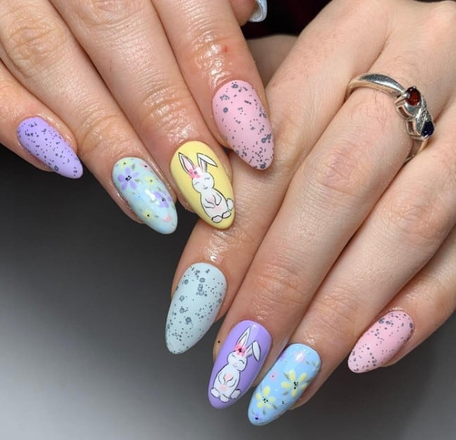 A woman's nails are decorated with bunnies and flowers while the other matte pastel nails are dotted to mimic an Easter egg design