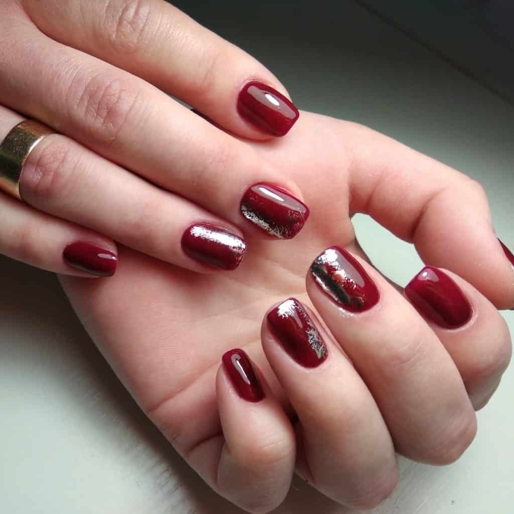 A woman's hand with deep burgundy nails will fulfill your wish, as the accent nails glisten with smears of silver foil