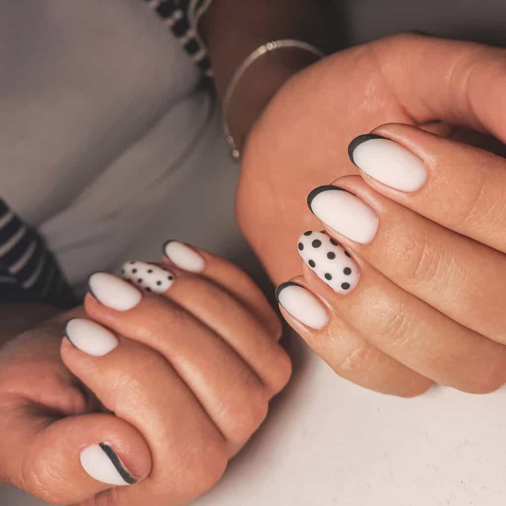 A woman's hands with pretty black-and-white polka dot nail design