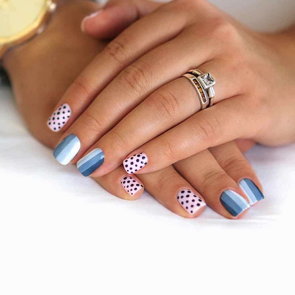 A woman's hands painted in white with  two classic nail patterns of stripes and dots