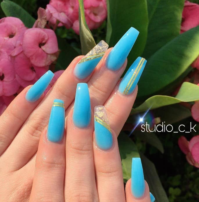 A woman with sky-blue coffin nail designs and gold accents.