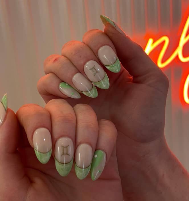 A woman with nude colored nails and light green nail polish with a marble effect