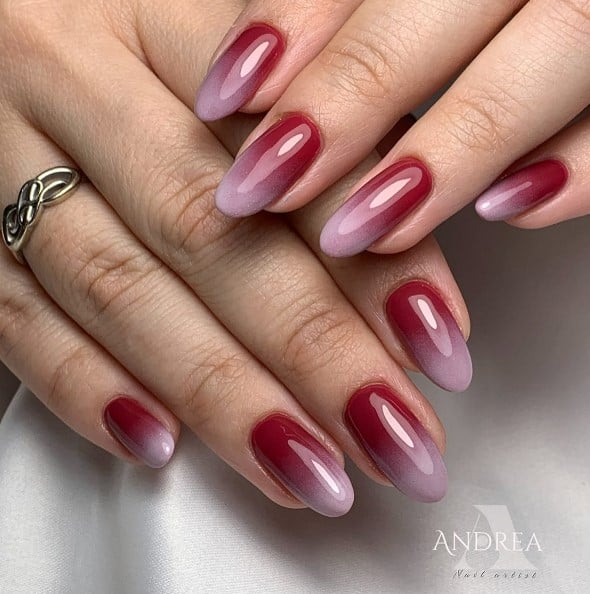 A woman's wine red nails that peters out to reveal mauve tips halfway through the nails