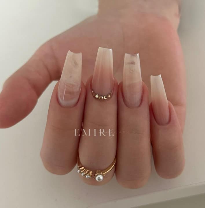 A woman's hand with light beige and soft pink ombre nails