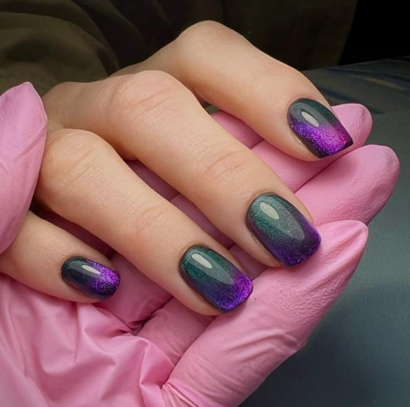 A woman with short nails captivate with their divine mix of dancing green, violet, and black hues