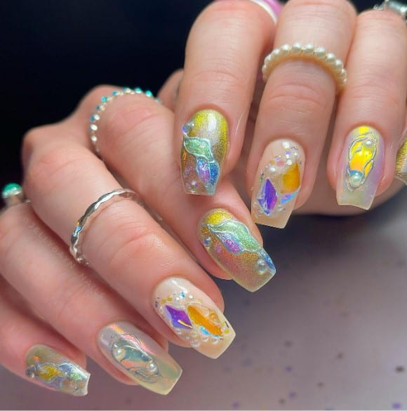 A woman's cat-eye nail design with delicate pearls and gems perch like precious treasures atop each clear nail with velvety gold-hued cat-eye patterns and 3D chrome lines