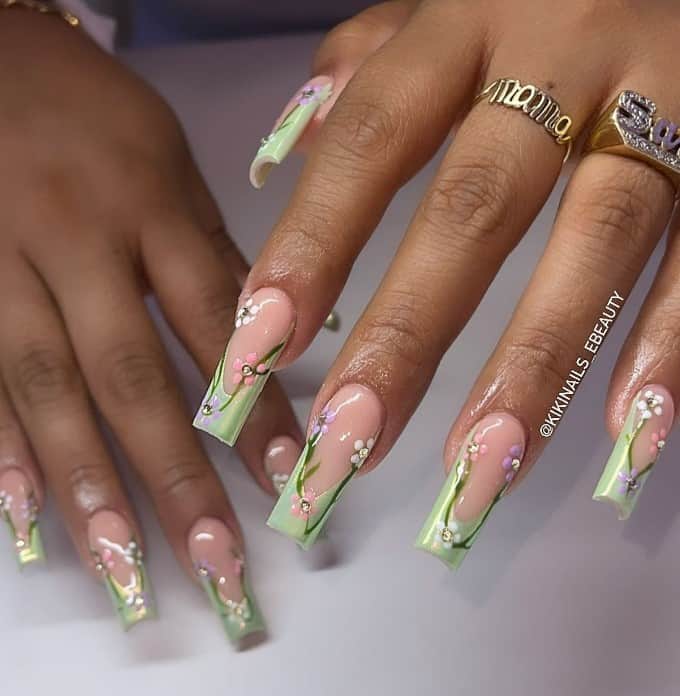 A woman's nails with pink and purple flowers and green vines over light green French tips