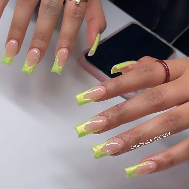 A woman with light green french tips and water splatter nail art over the nails