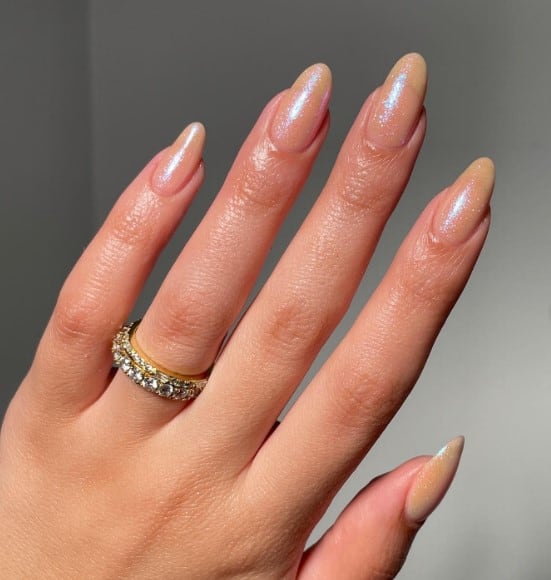 A woman's hand with nude base topped with an iridescent topcoat with subtle pink and blue shimmer
