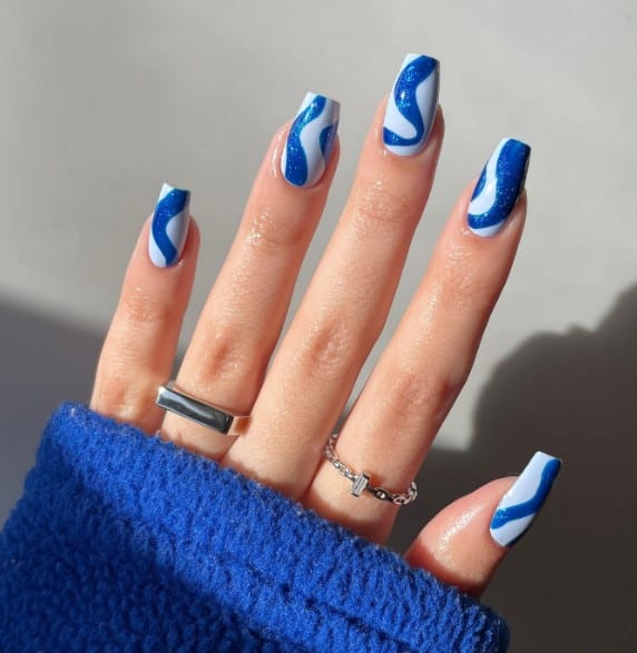 A woman's hand with groovy patterns featuring light and dark blue hues