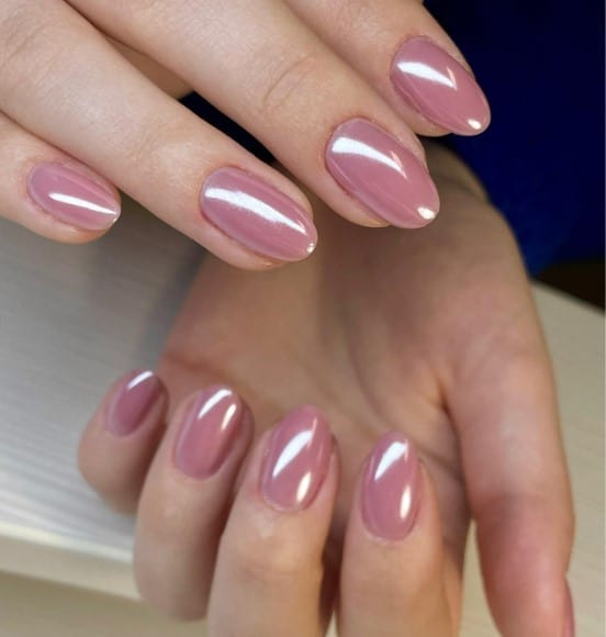 A woman with light pink nails with a glossy top coat 