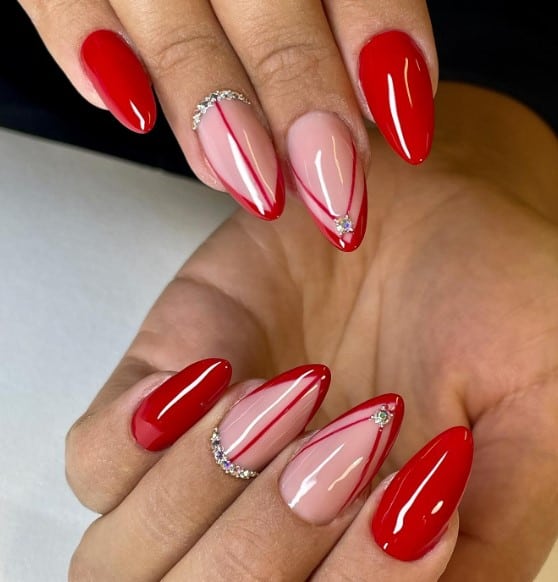 A woman's mani features red nails with two nude-colored accent nail designs with thin red French tips