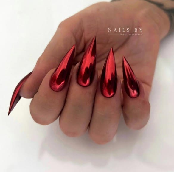 A woman's long stiletto nails with red chrome nail polish