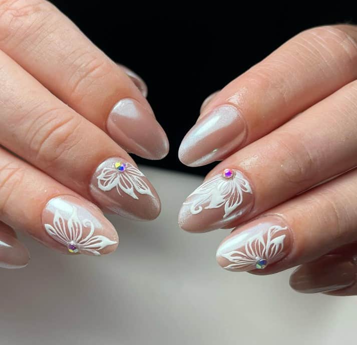 A woman's hands with iridescent pale pink polish and white flower nail art.