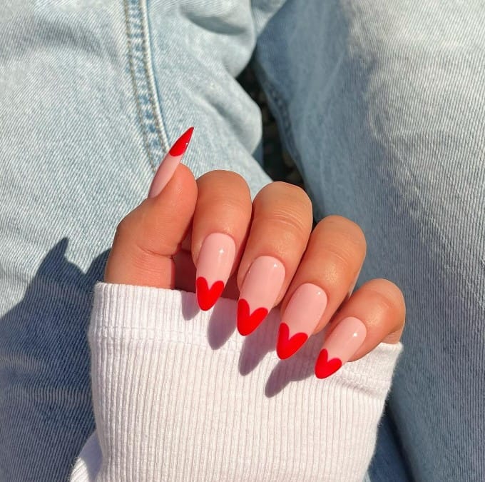 Each nail highlights heart-shaped French tips against a nude-colored base