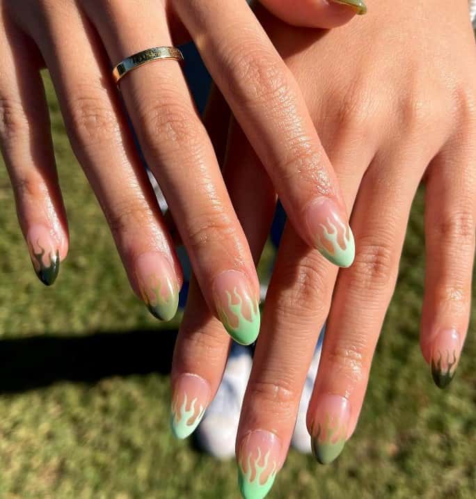 A woman's hands with nude colored nails and different shades of green from light to dark french tips