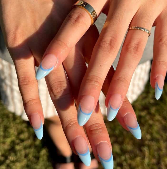 A woman's hands with light blue polish on the tips and a darker blue shade as a contrasting outline between the tinted tips and the bare base