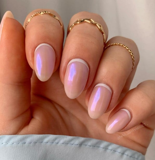 A woman's iridescent light pink nails with white reverse French tips