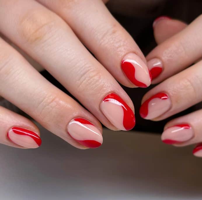 A woman's vertical red tips along the sides of nude-colored nails