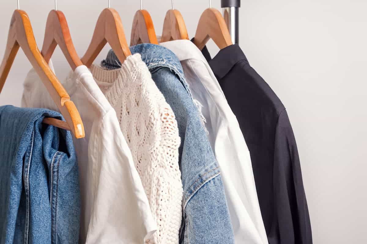 A rack of minimalist clothes hanging on a wooden hanger.