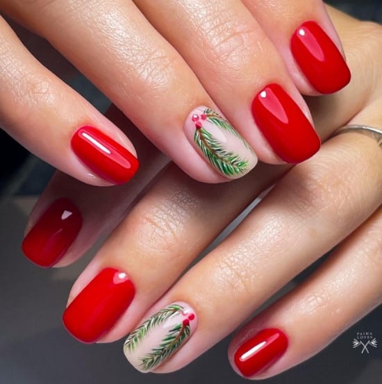 A woman's hand with bright red nails featuring accent nails with a Christmas mistletoe wreath art with pine leaves on a nude base