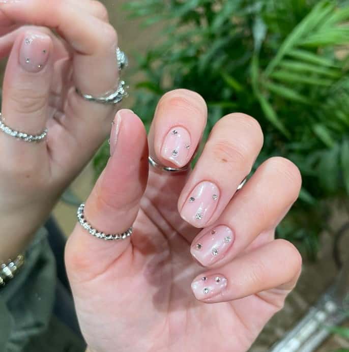 A woman's iridescent pink glazed donut nails with 3D silver rhinestones