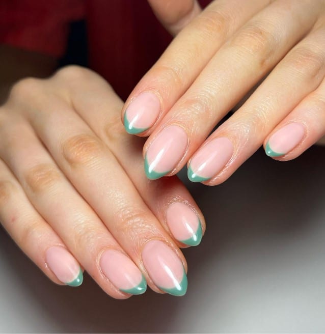 A woman's hands with thin French tip mani using blue-green nail polish