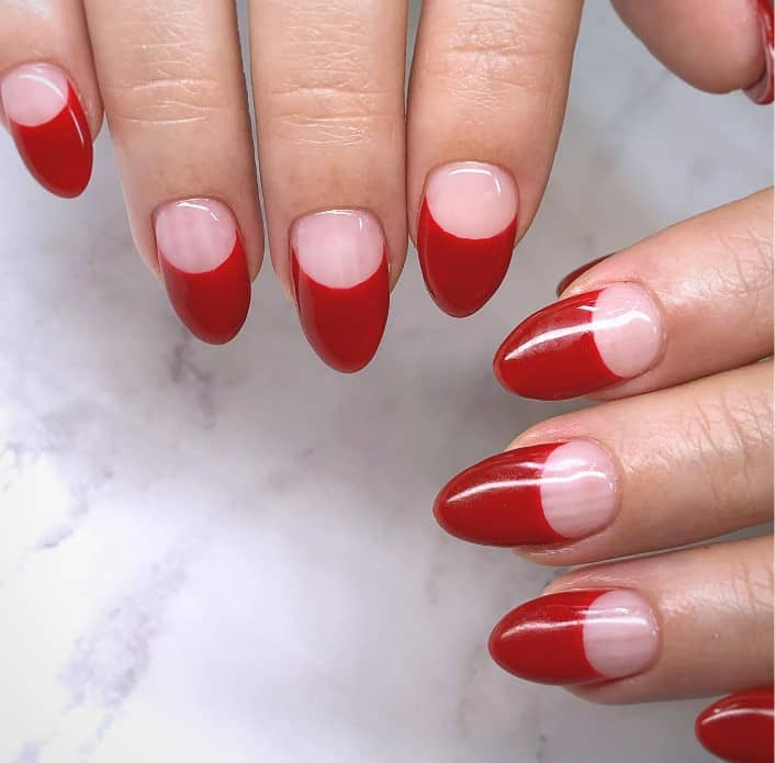 A woman's deep red nail polish on thick French tips occupying half the nail