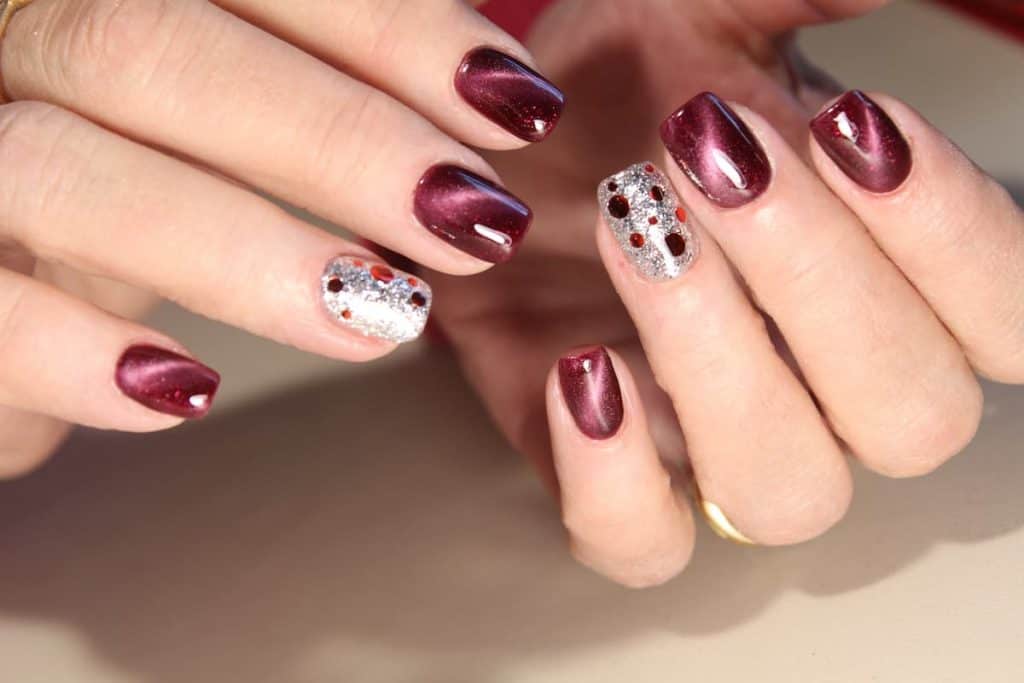 A woman's hands with a burgundy cat-eye design and silver accents