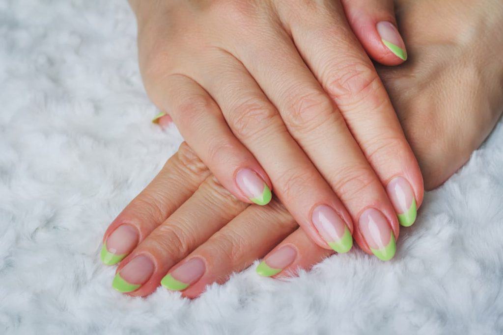 A woman's hands with green nails on a white background.