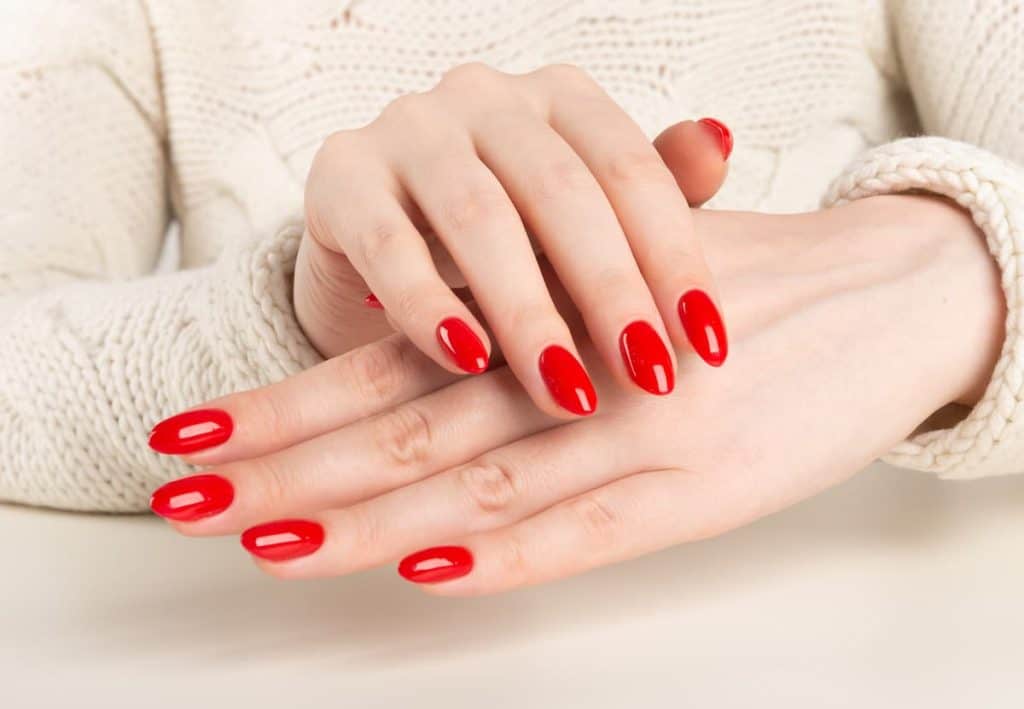 A woman's hands with red nails on a white table.