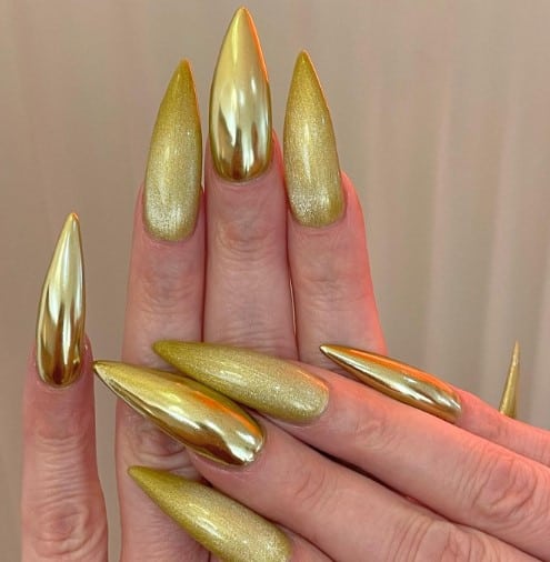 A woman's nails with gold nails by mixing metallic and glitter gold on sleek stiletto nails