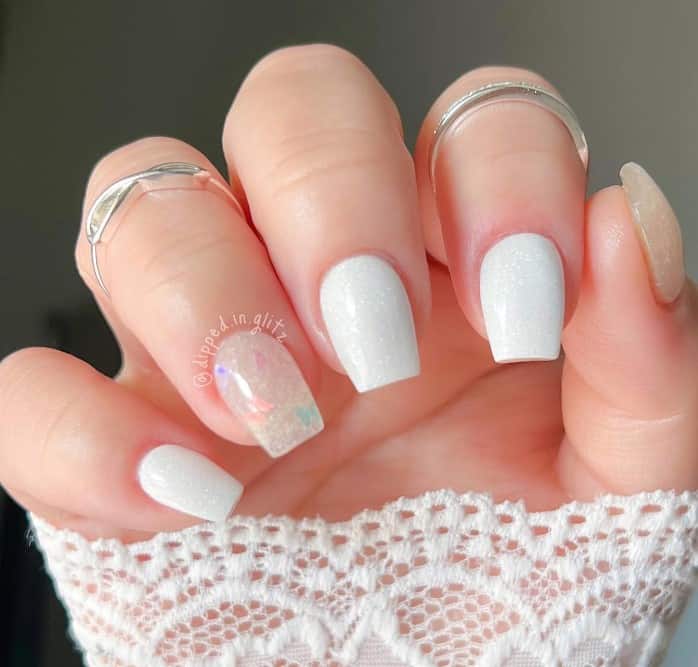 A woman's crisp white nails match the falling snow, complemented by two soft translucent thumb and ring fingernails with encapsulated butterflies