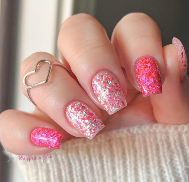 Square nails featuring a playful Barbie glam theme sprinkled with chunky confetti flecks in red and pink, while accent nails steal the show with shimmering silver and hints of pink and red
