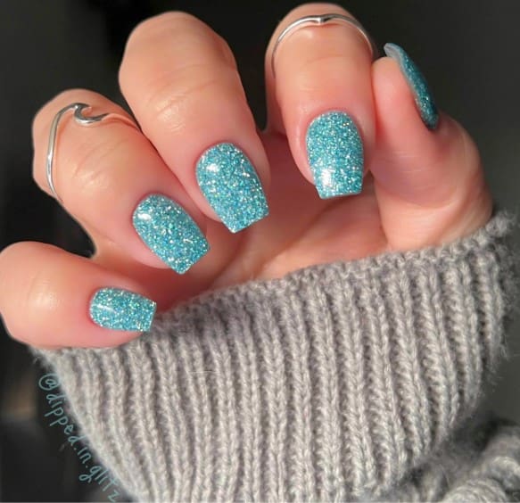 A woman's mid-length coffin nails adorned in enchanting sky-blue glitter
