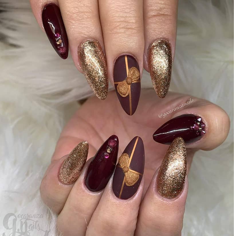 A woman's nails with gold, glittery nail polish shimmer alongside deep burgundy nails