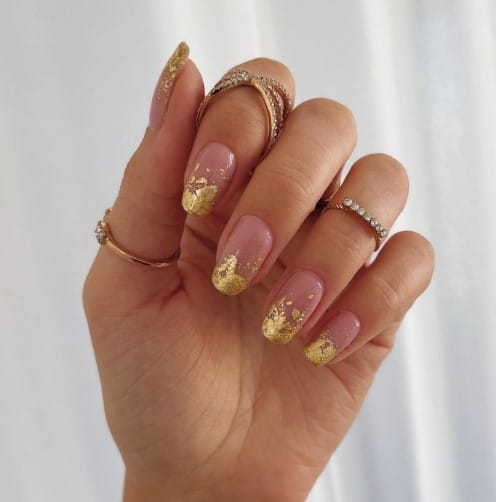 A hand with gold and pink painted nails.