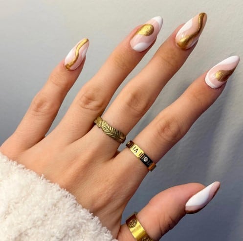 A woman with pink and white swirls mixed with a dash of glittery gold on nails