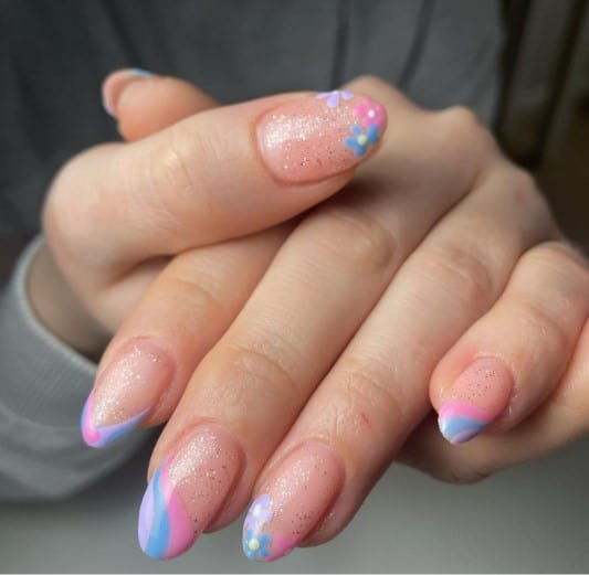 A woman's nails with soft peachy-pink hue and sprinkled with fine silver glitter