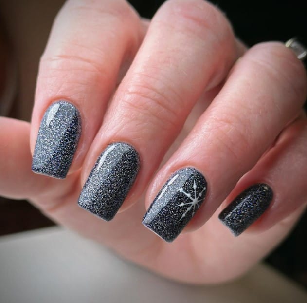 A woman's mid-length square nails an homage to a starry winter’s night with this glitter nail design for Christmas