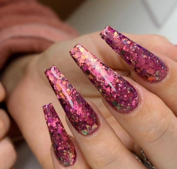 A woman's nails adorned with pink and purple glitter in stunning nail ideas.
