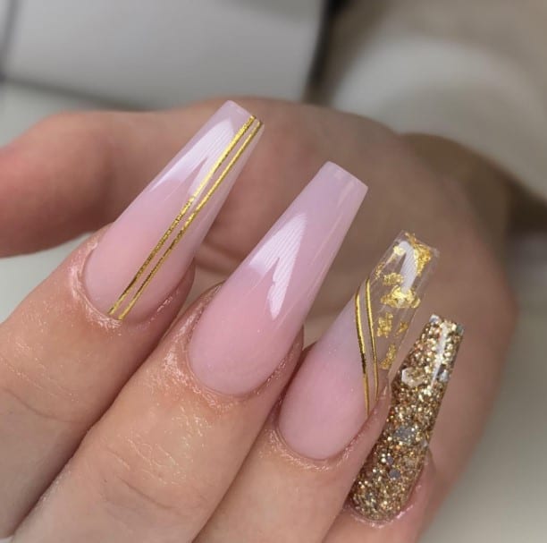 A woman's twin streaks of gold over pink nails and the full-on gold flakes on the little finger