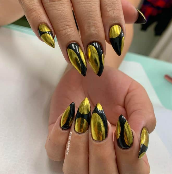 A woman's nails with combination of gold and black curves with a gleaming chrome finish 