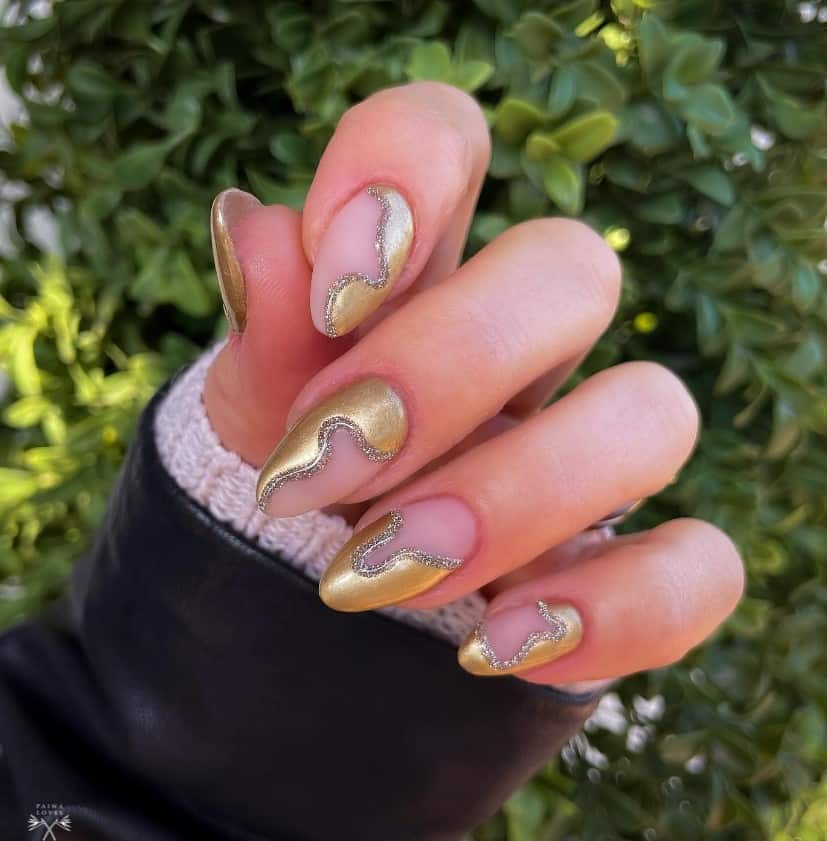 A woman's gold abstract shapes curving around in different angles on each nail lined in silver glittery nail polish